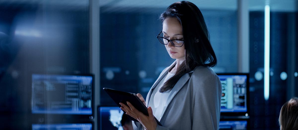 Woman standing in a futuristic office and using a tablet device