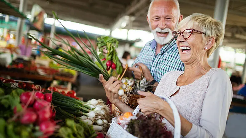 Pareja afluente viendo coloridas flores cultivadas localmente en un mercado