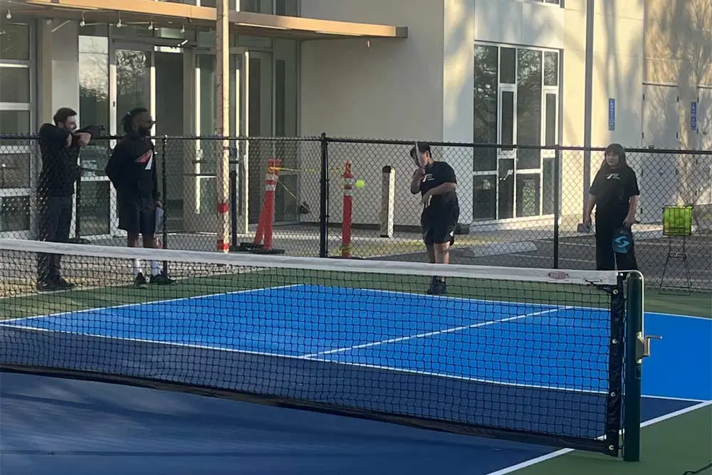 Kids playing pickleball with coaches watching