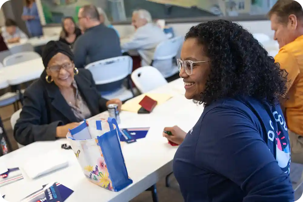 Woman in a U.S. Bank volunteer shirt smiling while talking to senior citizens