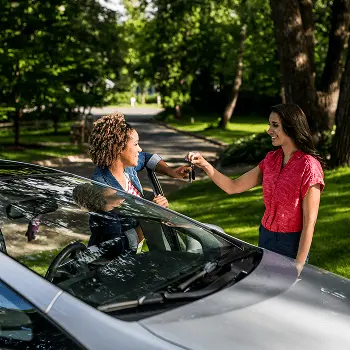 A private seller passing a car key to the person who purchased the used car with a personal loan.