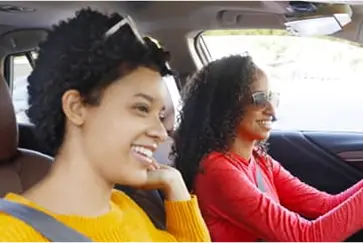 Woman driving car with a female passenger.