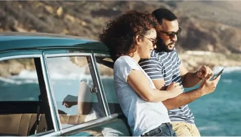 Couple leaning against car by lake