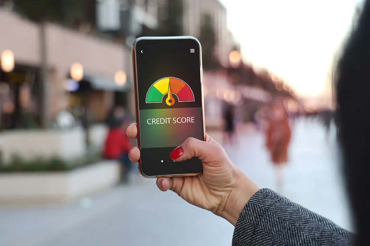 a hand holding a mobile phone while checking credit score