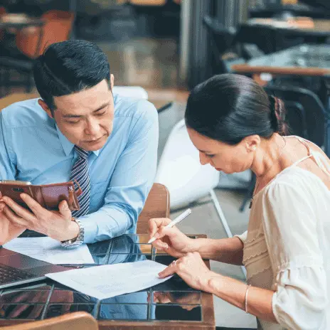 Man wearing a tie sitting with a woman who is writing notes about B2B payments
