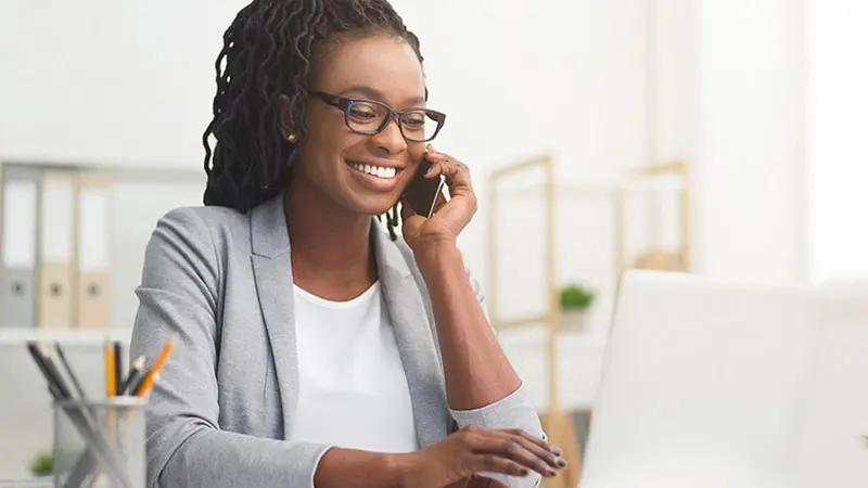 Woman talking on her phone while researching fund administration providers on her laptop