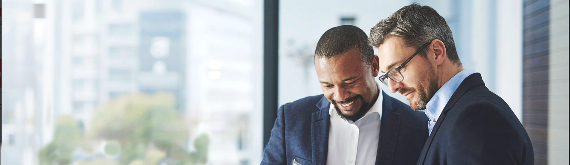 Professionally dressed colleagues, one man and one woman, standing inside an office