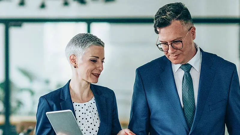 Man and woman wearing suits standing next to each other discussing corporate trust