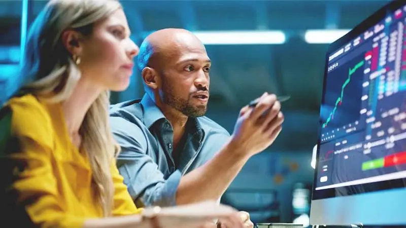 Man and woman analyzing currency on a computer