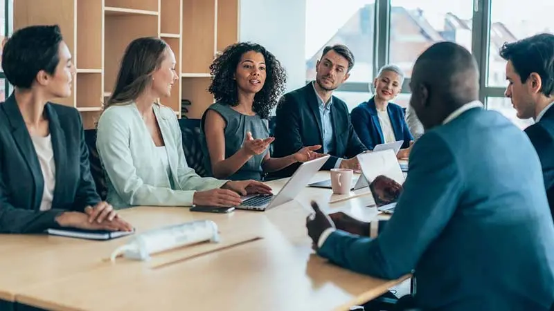 Office workers around a table discussing strategic alternative investment fund technology