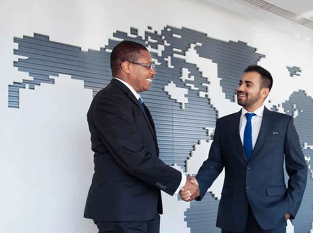 wo men in suits shaking hands in front of a large map of the world