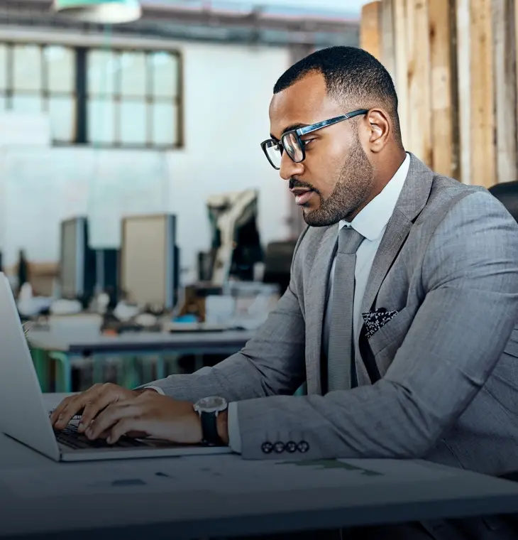 business man in grey suit and glasses working on a laptop