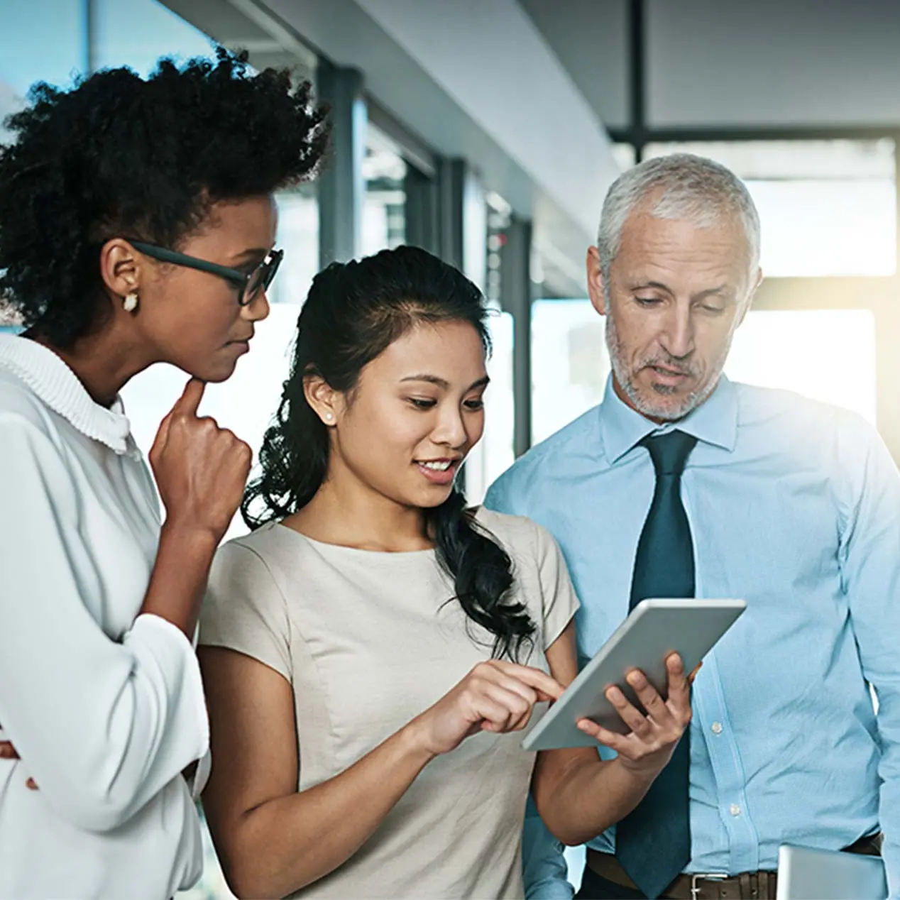 Two female and one male coworker standing together looking at interest rate derivatives 