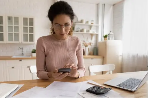 Woman in her kitchen using her phone to research how to pay her local government