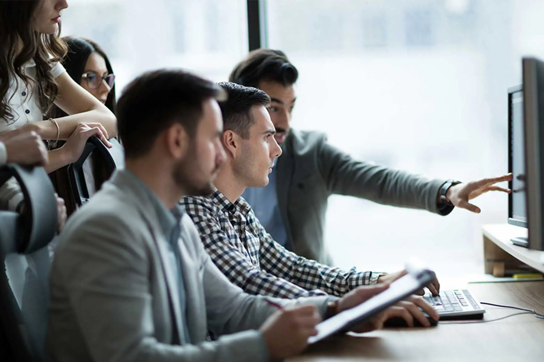 Group of 5 colleagues looking at a computer screen investigating fraud