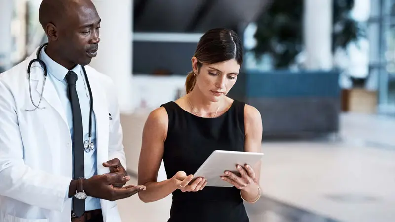 Healthcare provider and patient looking over a tablet looking over a patient refund receipt.