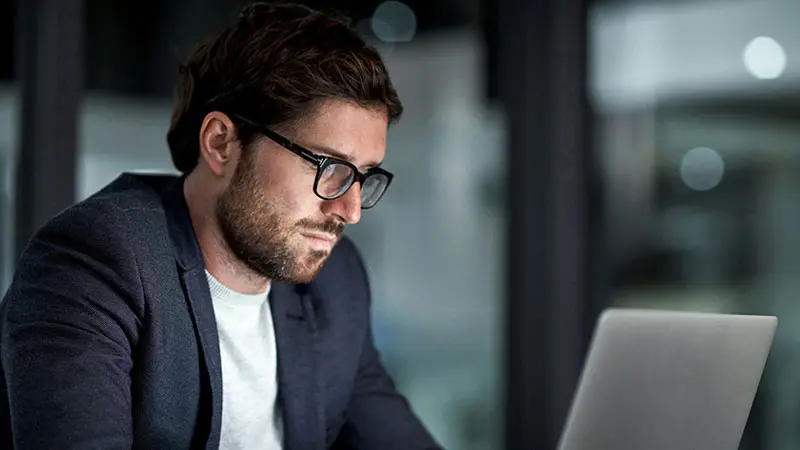 Bearded man wearing a blazer looking at his custody account on a laptop