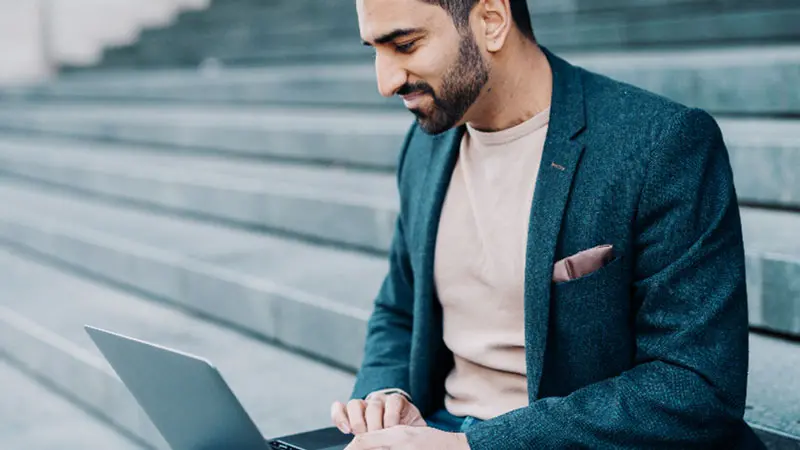 Man on computer looking up banks that can do cryptocurrency custody.