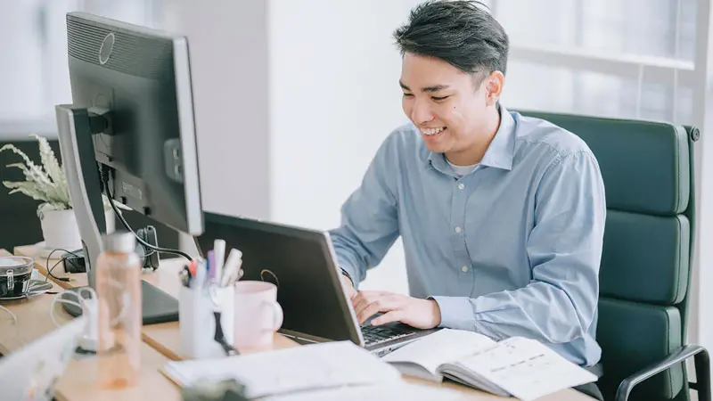 Young professional sitting at workstation researching escheatment rules in his state