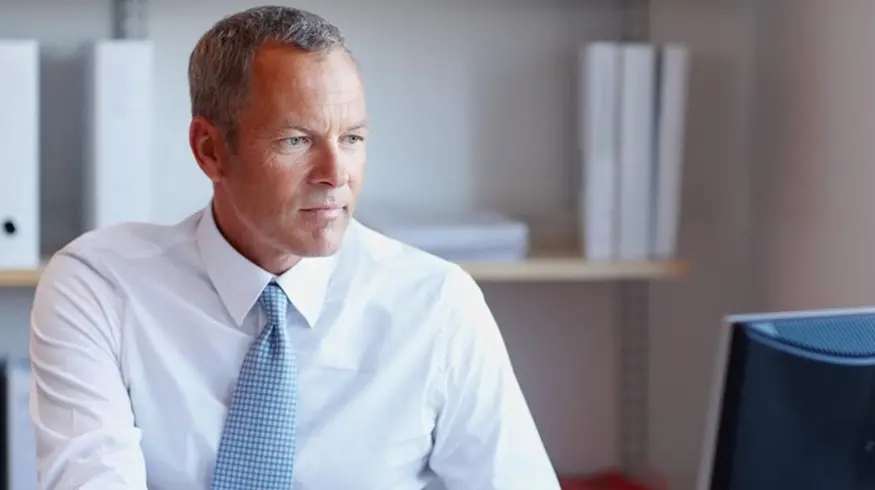Office professional wearing a tie and reading about business email compromise on his work computer