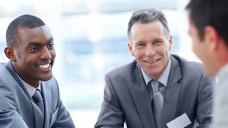 Three men in suits discussing employee benefit plans