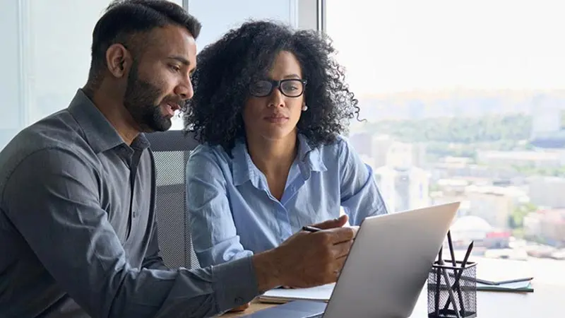 Man and woman sitting at a desk with a laptop evaluating their interest rate risk management strategy