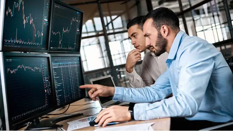 Two men looking at international payment graphs and comparing ach vs wire transfer.