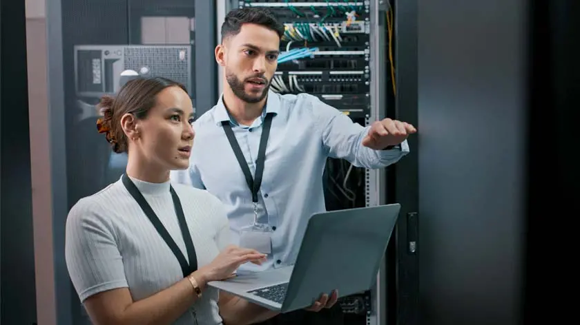 Two IT workers in a server room doing an inspection