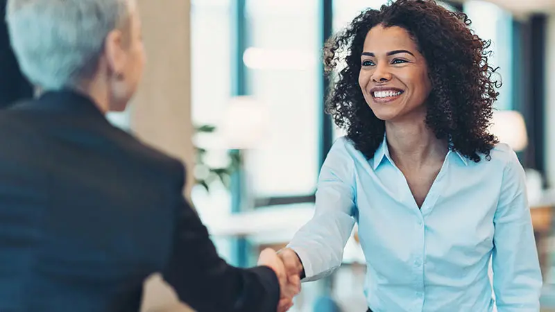 Two professional women shaking hands after a meeting about asset custody