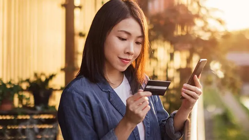 Woman holding phone and looking at best commercial credit card options