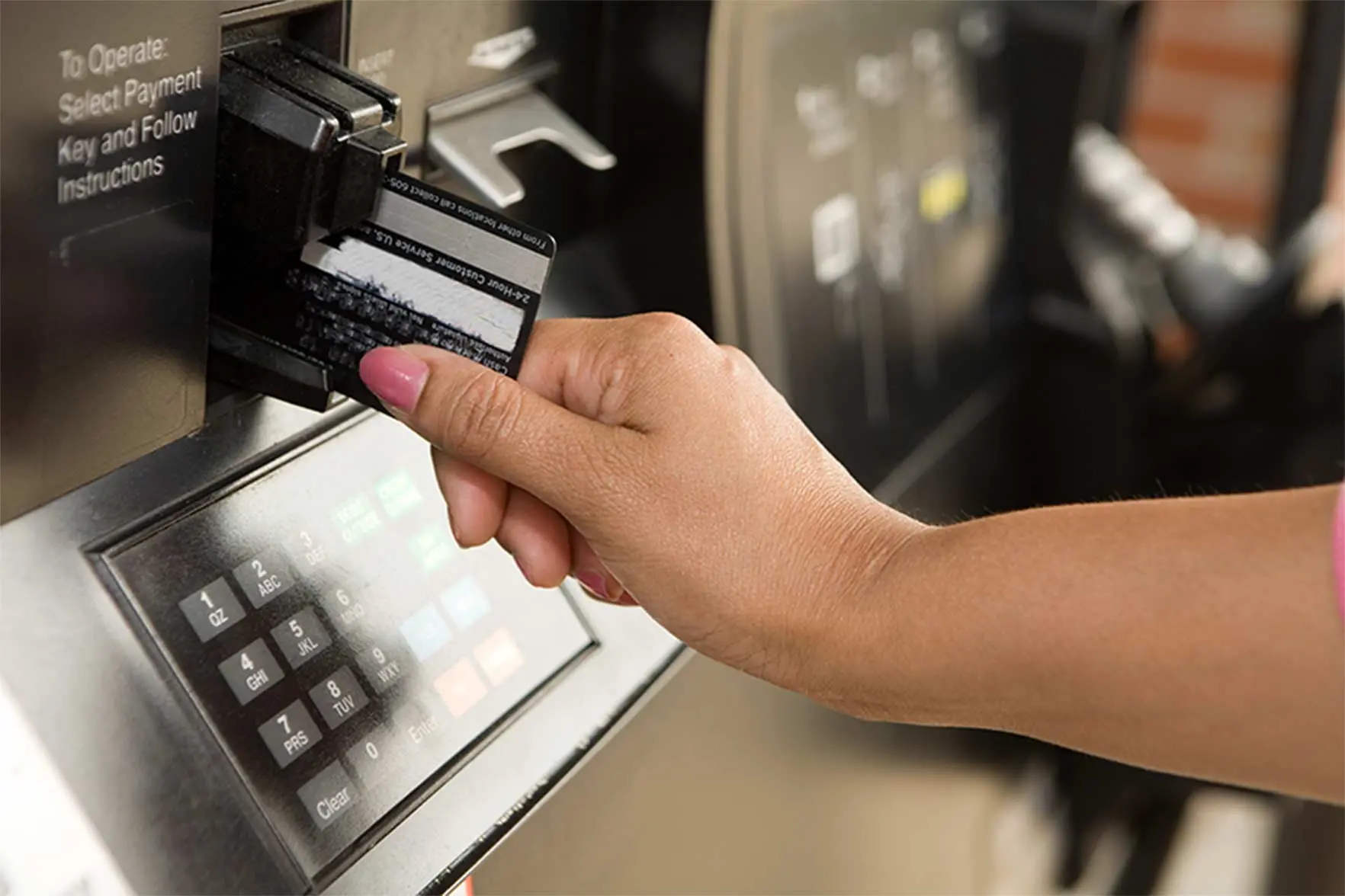 Closeup of a woman's hand inserting a credit card into an ATM