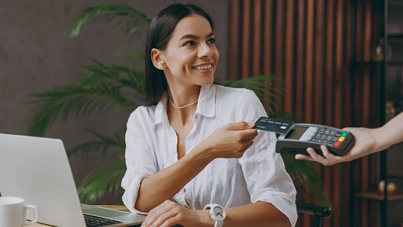 Woman tapping her credit card to pay at a processing machine