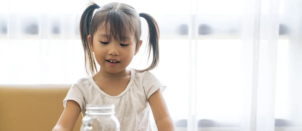 young girl in pigtails looking at coins