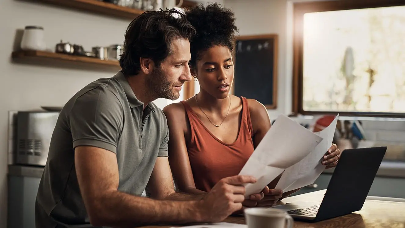 a man and woman looking at paperwork in their kitchen