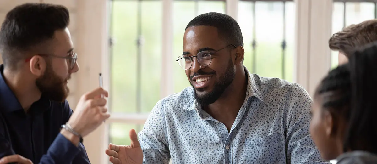 a man in a blue and white shirt and glasses talking to other people