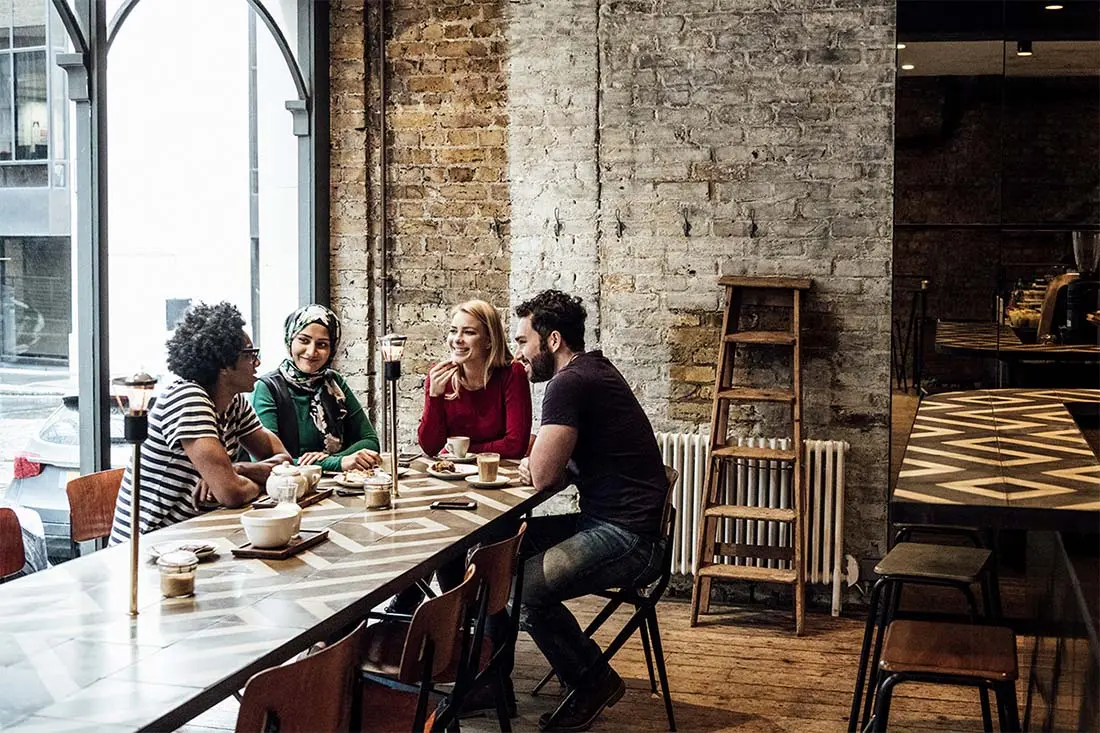 a group of friends sitting at a table in a coffee shop