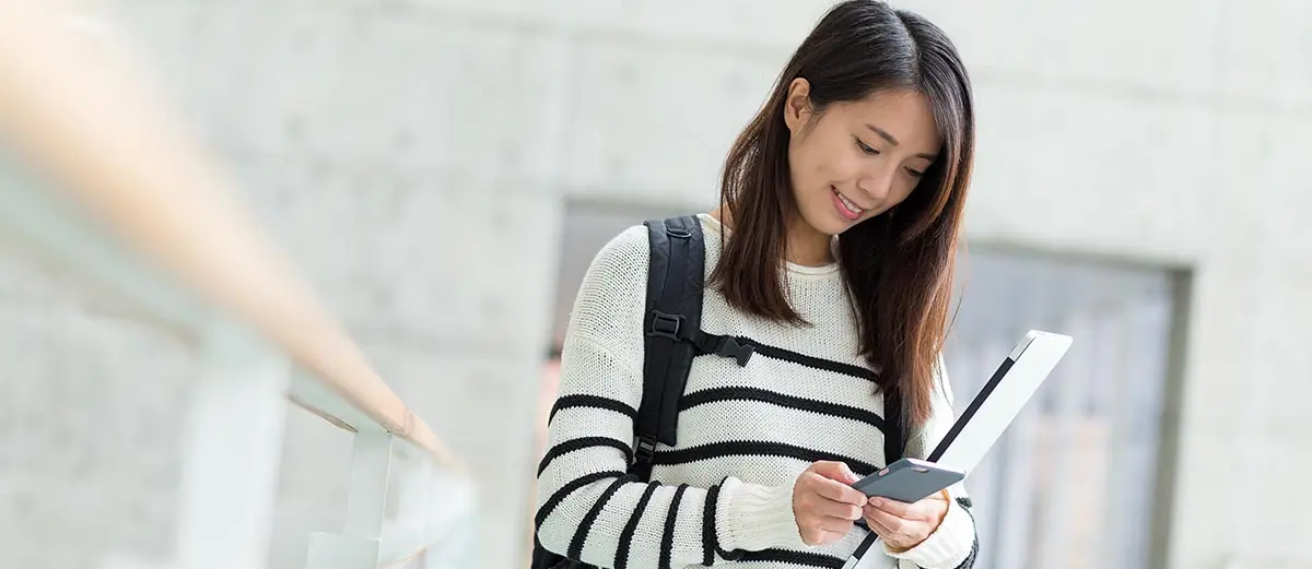 a woman in a black and white striped sweater looking at a mobile phone