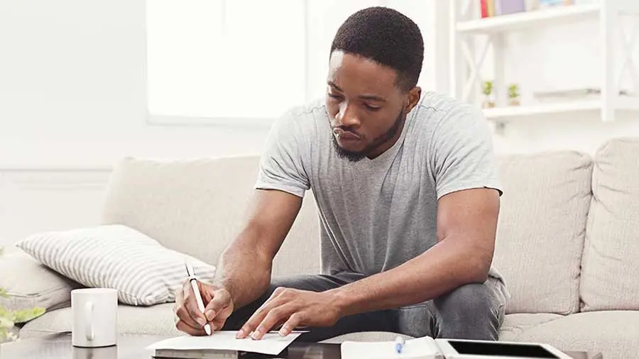 man in a grey shirt taking notes on a coffee table