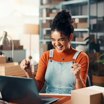 Woman wearing overalls celebrating by computer