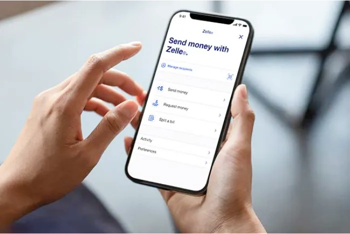 Send money with Zelle screen on a smartphone held in someone’s hands