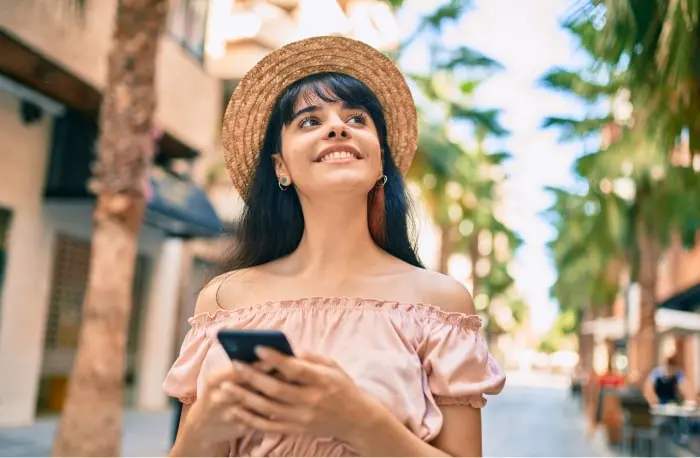 Smiling consumer on an outdoor promenade looking up from her phone