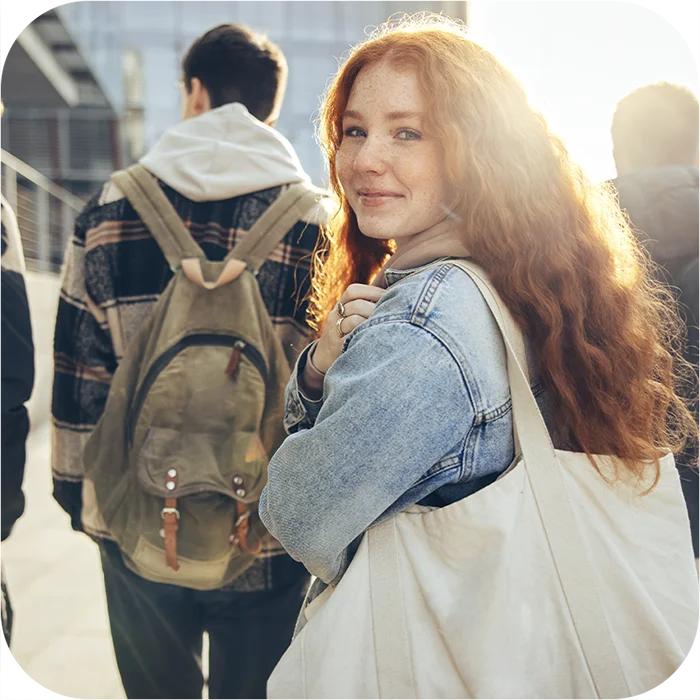 Teen looking back and smiling while walking on campus with other high school students
