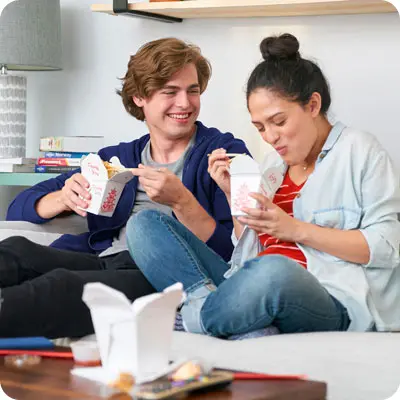 Couple enjoying takeout thanks to smart money management with overlays displaying monthly spending and progress toward savings goals