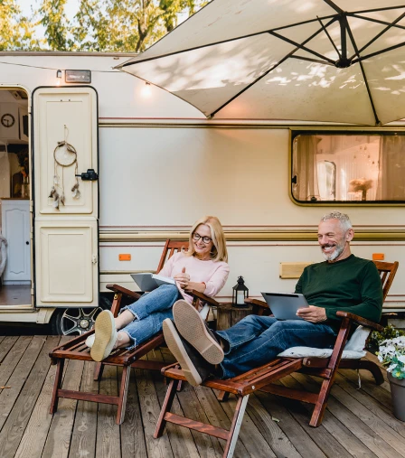 Middle-aged couple sitting in lounge chairs outdoors in front of their RV
