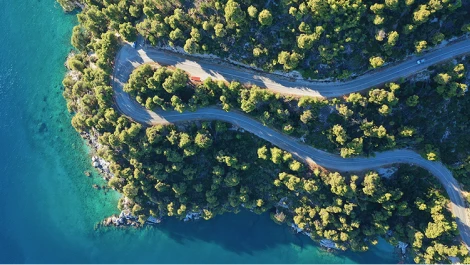Aerial view of a highway winding through a forest along a coastline