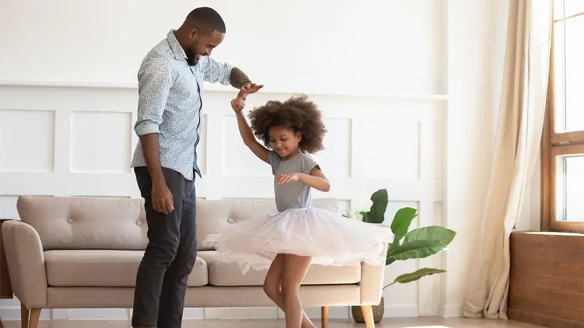 african-american father dancing with daughter in their living room