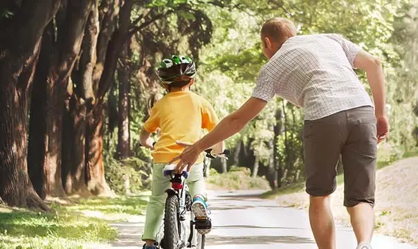 young father teaches his son how to ride a bike