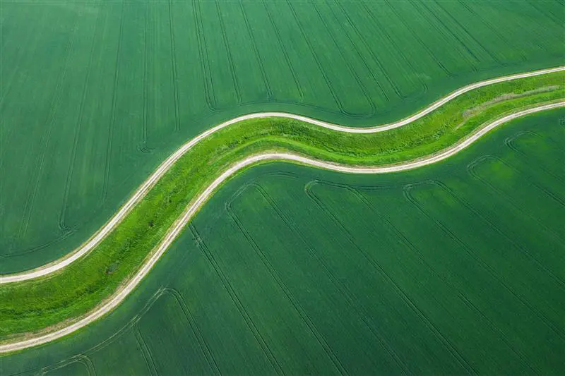 Aerial view of a farm field with a winding road running through it