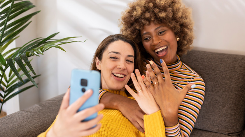 multiracial couple sharing wedding rings with friends on the phone