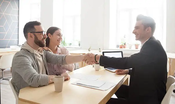 Young couple shakes hand of accoutn manage in office